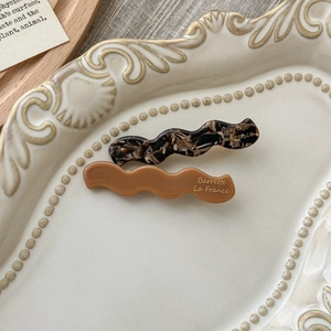 Detailed macro view of wavy acetate hair clips in tortoiseshell and solid brown colors