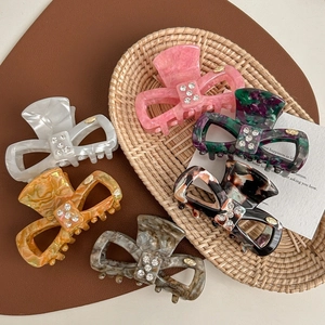 Bow-shaped acetate hair claws with sparkling rhinestones in a set of six colorful styles