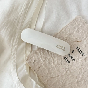 Detailed close-up of cream acetate hair clip with gold France Handmade lettering