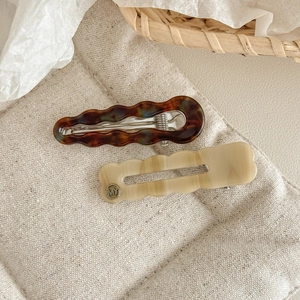 Détails de pinces à cheveux ondulées en acétate avec textures écaille et beige crème