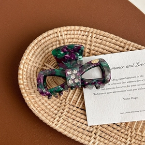 Close-up of marble acetate hair claw clip with rhinestones on a woven tray
