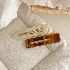 Détail macro de barrettes à cheveux en acétate ondulé, motifs marbre et ambre, style coréen
