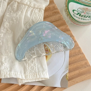 Détail d'une pince à cheveux en acétate bleu clair avec finition irisée sur dentelle