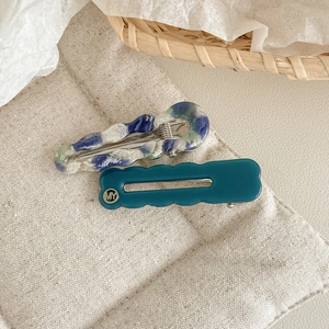 Détail de deux pinces à cheveux en acétate avec texture marbrée sur une surface en lin tissé