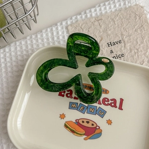 Détail d'une pince à cheveux fleur vert forêt à texture marbrée sur une assiette