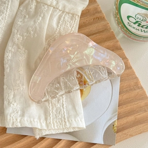 Détail d'une grande pince à cheveux rose nacré aux courbes douces sur tissu blanc