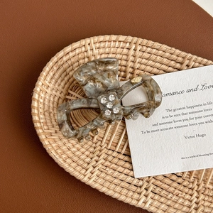 Detail of tortoise shell acetate hair claw with rhinestones on woven tray