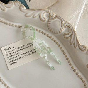 Detailed macro shot of U-shaped marble green acetate hair pin in a decorative tray