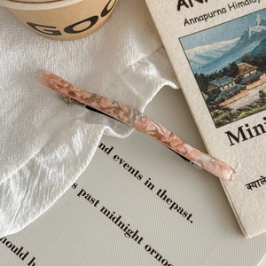 Détail d'une barrette en acétate floral avec pétales séchés sur fond de livre ancien