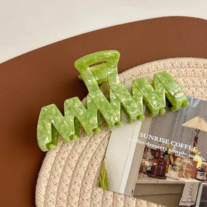 Macro detail of a large wavy light green acetate hair claw clip with a marble texture