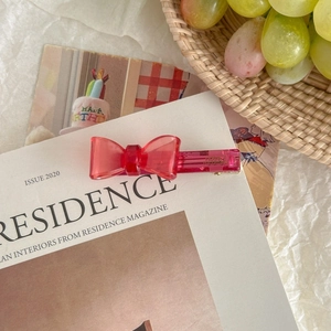 Détail d'une pince à cheveux rose faite main avec gravure sur un magazine de mode