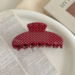 Close-up of a large red and white polka dot hair claw clip on a stylish decorative plate