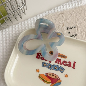 Détail de la pince papillon en acétate bleu-violet avec logo métallique gravé