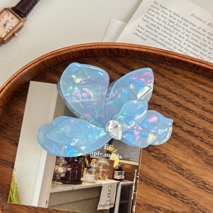 Détail de la pince à cheveux papillon en acétate bleu iridescent avec strass brillant