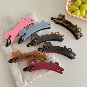Handmade cat-shaped banana hair clips in various colors displayed on a linen bag