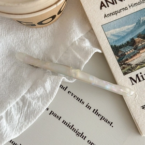 Détail d'une barrette en acétate faite main avec texture marbrée irisée sur un livre