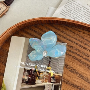 Détail de la pince à cheveux fleurie bleu clair irisé avec un strass en forme de larme