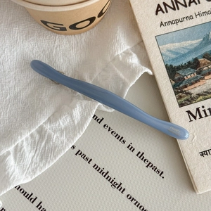 Détail d'une pince à cheveux en acétate bleu avec inscription France Handmade sur lin