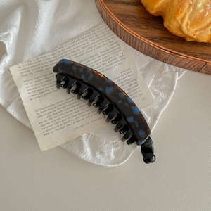 Close-up of tortoise shell banana hair clip with double teeth on a vintage linen background