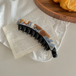 Close-up of a marbled tortoise shell banana hair clip on vintage paper background