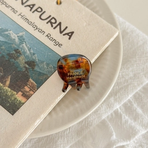 Detailed close-up of mini tortoiseshell acetate hair claw clip with gold handmade engraving