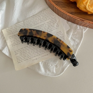 Detail of banana hair clip with dark brown tortoiseshell pattern and black inner comb teeth