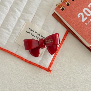 Detail of red acetate bow hair clip with gold France Handmade lettering on quilted mat