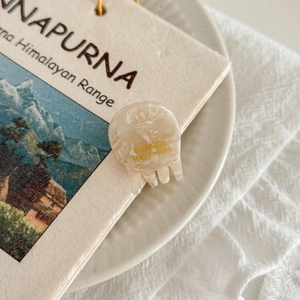 Detailed macro view of handmade marble white acetate hair claw with gold stamp logo