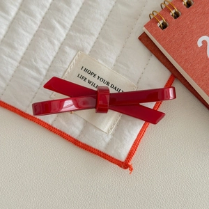 Detailed macro view of the glossy dark red acetate bow hair clip with high shine finish