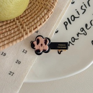 Detailed macro view of a leopard print flower hair clip with France Handmade lettering