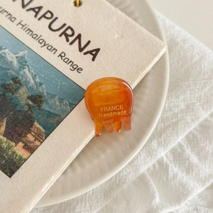 Detailed close-up of a mini amber acetate hair claw with gold France Handmade logo