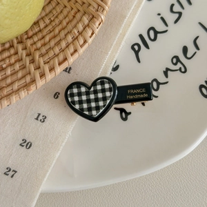 Detailed close-up of heart-shaped hair clip with black and white checkered pattern
