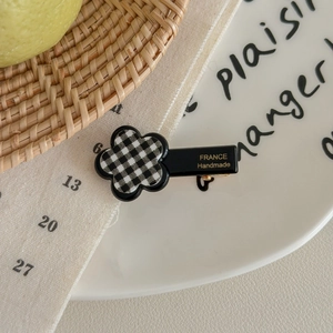 Macro detail of checkered flower hair clip with golden France Handmade engraving