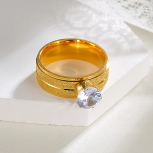 Luxuriöser goldener Ring mit strukturierter Oberfläche und Zirkon auf weißem Steinsockel
