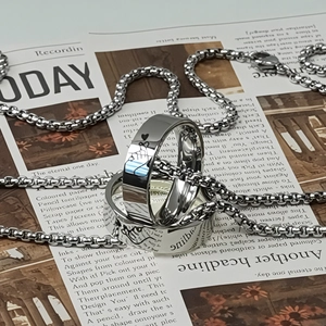 Polished silver couple rings and box chain necklace with heart hands on vintage newspaper