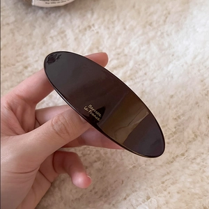 Minimalist dark brown acetate barrette with gold French lettering on soft plush background