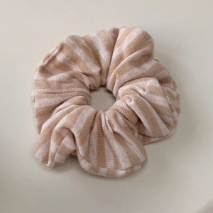 Détail d'un chouchou en maille rayé beige et marron avec une texture douce et souple
