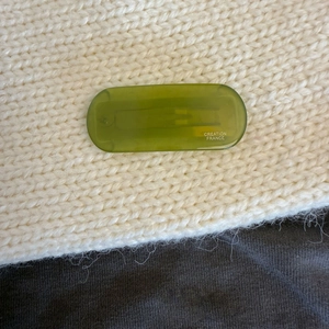 Close-up of a translucent green acetate hair clip featuring Creation France text on a knit background