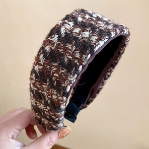 Close-up detail of a wide houndstooth plaid knitted headband with warm wool texture