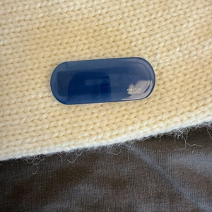 Close-up of a dark blue oval acetate hair clip with Creation France logo on knit fabric
