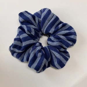 Gros plan sur la texture tricotée du chouchou à rayures bleues avec détail élastique