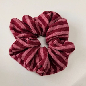 Gros plan sur la texture tricotée à rayures rouges et roses d'un chouchou élastique doux