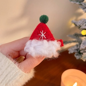 Détail d'une pince à cheveux bonnet de Noël rouge avec flocon brodé et pompon vert