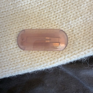 Detail of lavender acetate hair clip with gold Creation France logo on knit background