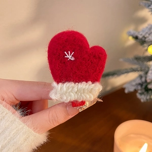 Détail d'une pince à cheveux gant en tricot rouge avec broderie flocon de neige
