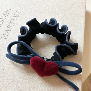 Macro detail of velvet heart and denim bow on a black pleated scrunchie accessory