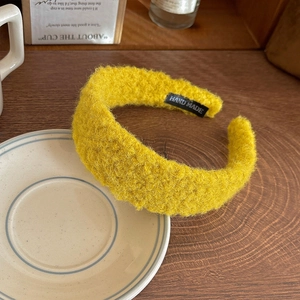 Retro wide-brimmed yellow felt headband with handmade label on wooden tabletop