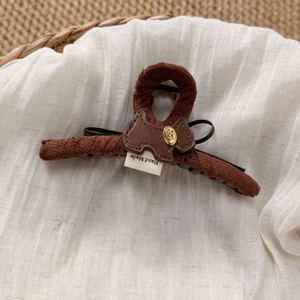 Macro view of handmade dark brown plush hair claw with leather puppy patch detail
