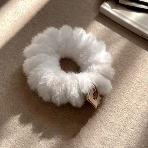 Gros plan d'un chouchou blanc en peluche avec étiquette cerf sur tissu texturé