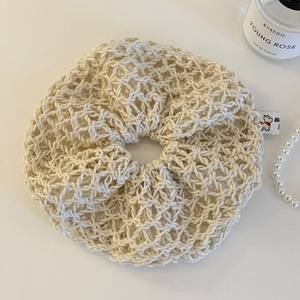 Close-up of beige crochet hair scrunchie with hollow out mesh texture and puppy tag